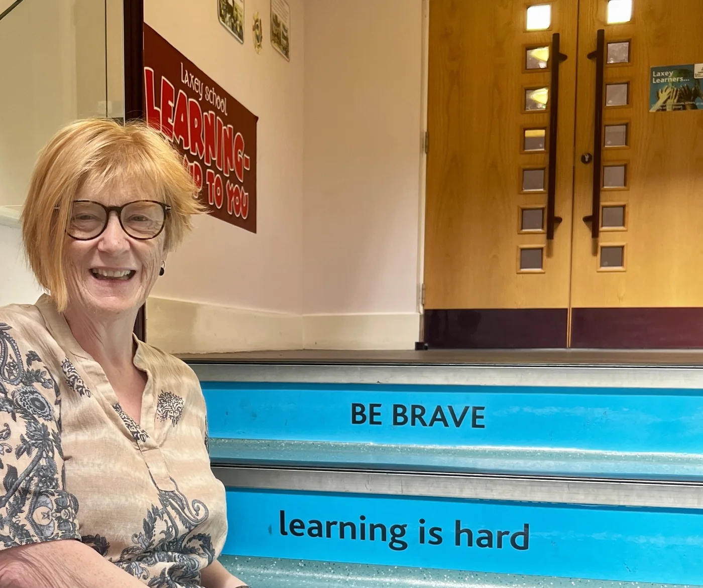 Carol beside a Be Brave message