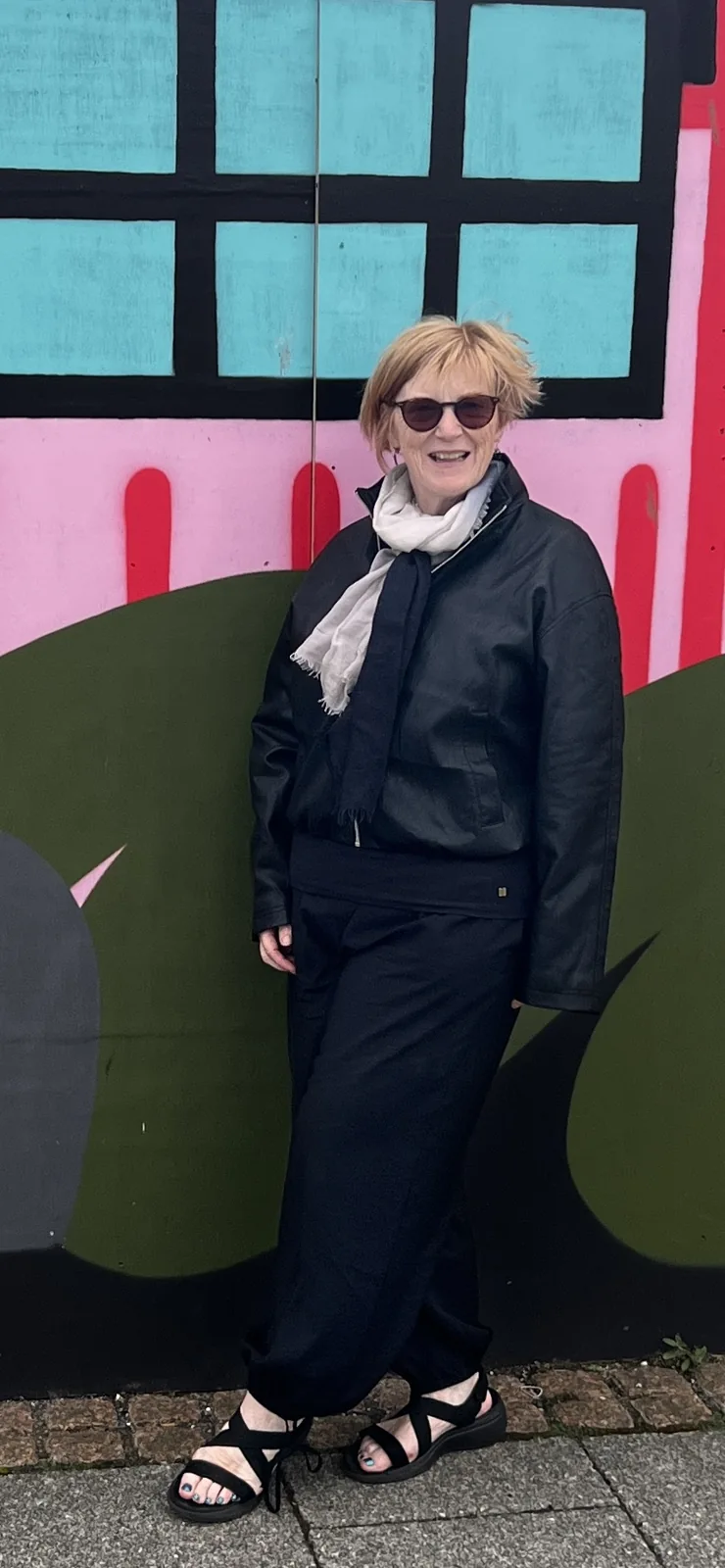 Carol smiling in front of a colourful wall