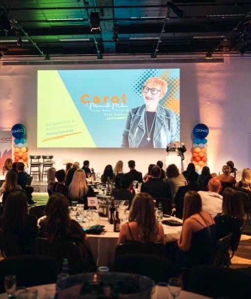 Carol Glover speaking to a large audience
